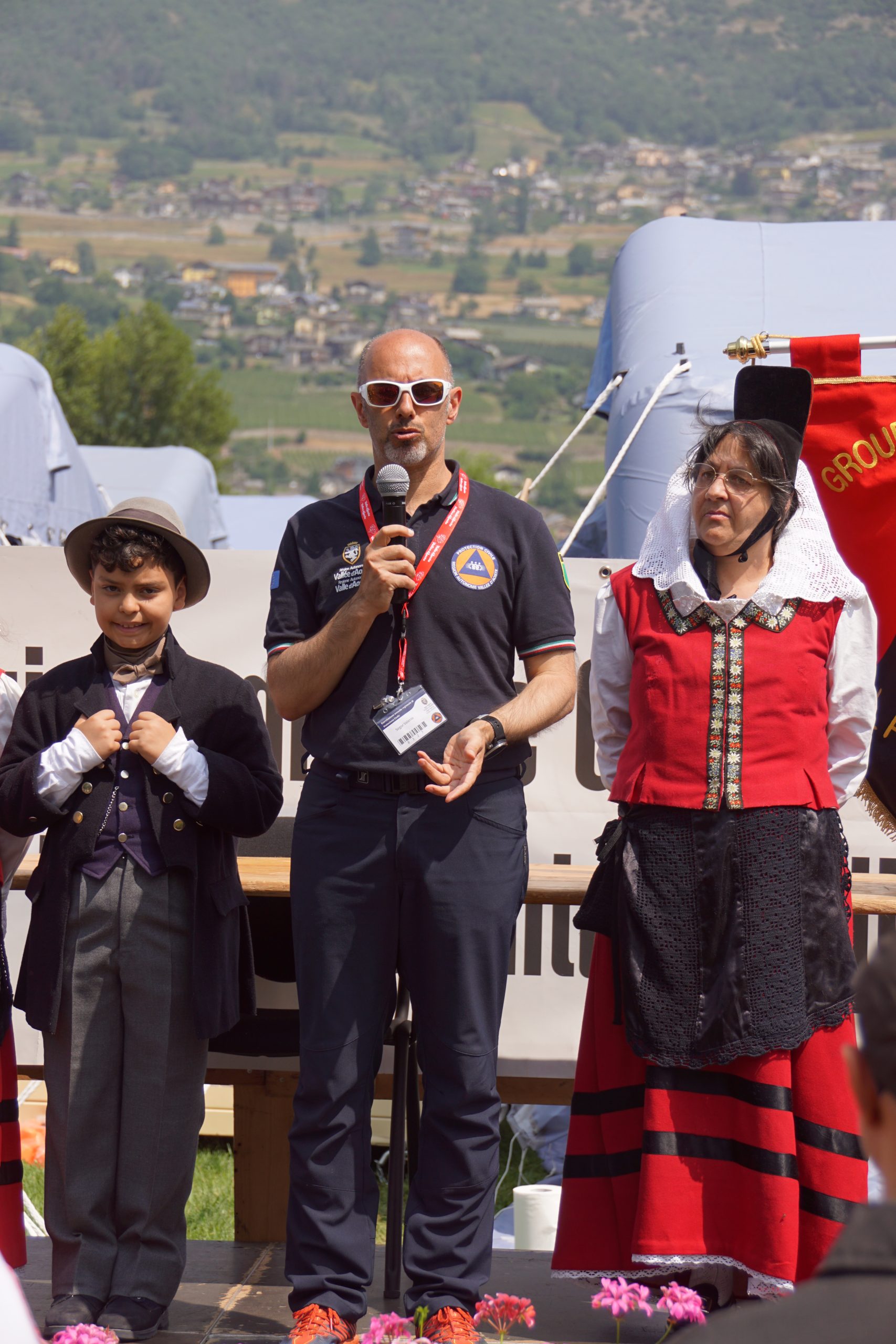 Valerio Segor pronuncia il suo discorso durante la Cerimonia conclusiva, in mezzo a due componenti de La Clicca